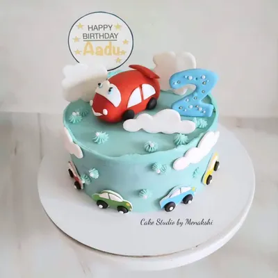 A cute car themed cake for a second birthday. This blue buttercream cake is decorated with a red car on top and little cars driving around the sides.