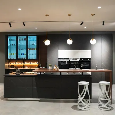 A stunning example of a dark and dramatic kitchen from our Coimbatore showroom. The combination of dark stone-finish cabinets, a wooden bar top, and back-lit glass units creates a luxurious, moody atmosphere perfect for entertaining.