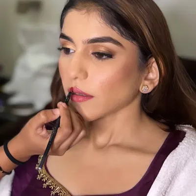 A classic behind-the-scenes shot from a bridal session. This image captures the focused moment of applying lipstick, a crucial final step in perfecting a bride's look and ensuring every detail is flawless.