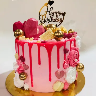 This vibrant pink drip cake is a party in itself. It's loaded with geometric chocolate hearts, white chocolate bars, and shiny golden spheres for a fun and luxurious birthday celebration.