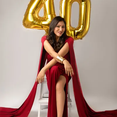 Turning forty is a power move, and this portrait is all about celebrating it. Dressed in a stunning red gown with cape sleeves, she looks absolutely radiant and ready to conquer her next decade.