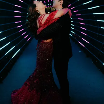 A couple shares a joyful, romantic moment inside a tunnel of neon lights. This shot from a Sangeet or Cocktail night showcases our ability to use creative lighting to capture modern, dynamic portraits.