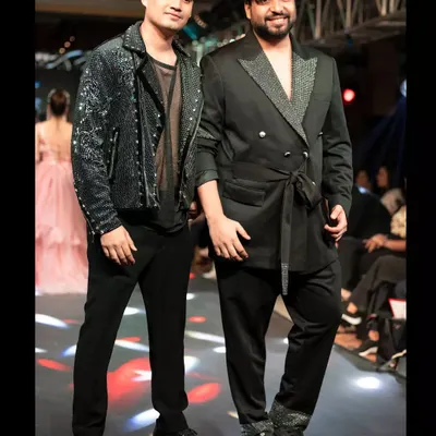 On the runway with my showstopper Deep, who is wearing a custom black sequined jacket. The look is layered over a sheer black top, showcasing an edgy and glamorous style for men.