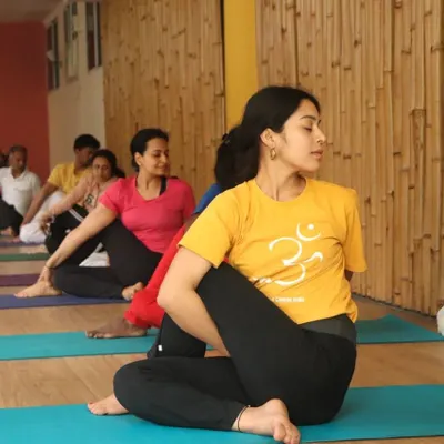 A student practices Ardha Matsyendrasana (Half Spinal Twist) during a group class. This posture energizes the spine, stimulates the liver and kidneys, and improves digestion.
