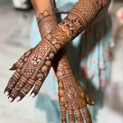 Gayathry's stunning wedding mehendi, featuring her and her partner's initials "BG" and a yin-yang symbol, surrounded by dense, traditional Indian patterns.