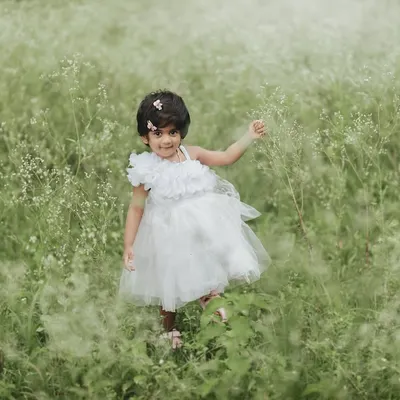 A little angel in a field of dreams. This toddler in a white dress looks so serene and beautiful surrounded by the soft greenery of nature.