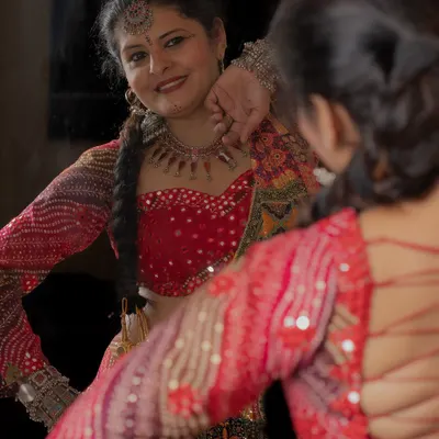 Getting ready for Navratri in a bespoke Garba outfit. This mirror-work blouse and colorful lehenga are designed for dancing the night away.