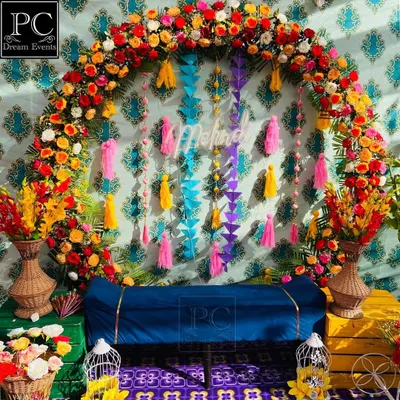 A riot of colors for a beautiful Mehndi ceremony. I designed this backdrop with a dense floral arch, a patterned teal wall, and colorful hanging tassels for a rich, layered look.