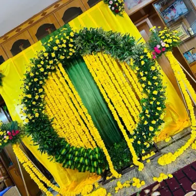 A classic Haldi ceremony decoration, featuring a large circular arch made of lush green leaves and bright yellow marigolds. The hanging flower strings add to the festive feel.