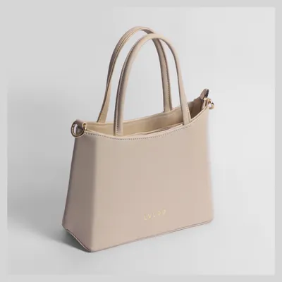 A clean, elegant shot of a beige women's handbag. This 3/4 view is perfect for showcasing the bag's shape and structure.