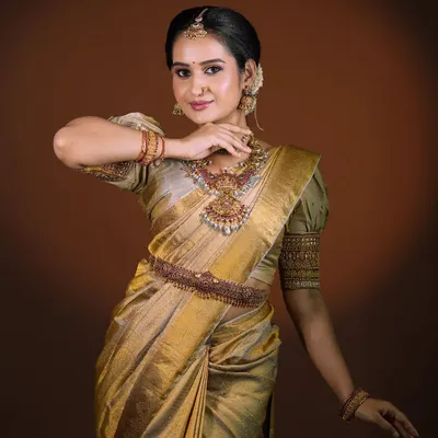 A polished and regal bridal portrait. This look features a stunning golden silk saree, complemented by temple jewelry and makeup that highlights the bride's natural elegance.