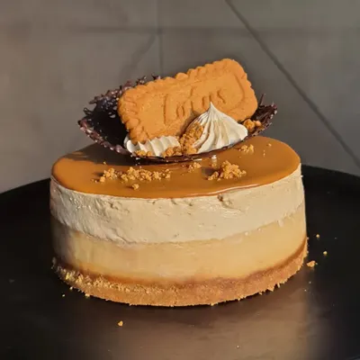 A close-up of my mini Biscoff cheesecake. It has a crunchy biscuit base, a creamy cheesecake layer, and is topped with a smooth Biscoff spread, a chocolate lattice, and a Lotus biscuit.