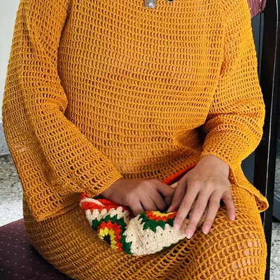 A closer look at the mustard crochet dress, showing the texture of the stitch work and how it drapes beautifully when seated.