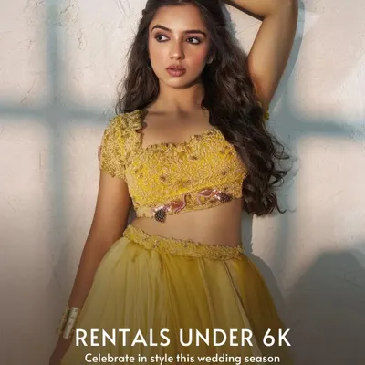This image announces our collection of stunning rentals available for under 6k. The model is wearing a beautiful yellow embroidered lehenga, perfect for a haldi or mehendi ceremony, proving that you don't have to spend a lot to look amazing.