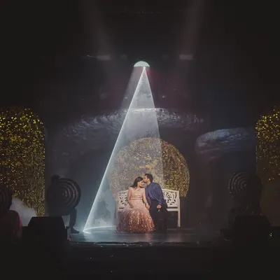 A quiet moment for the couple on a stage designed to feel like another dimension. A single beam of light creates an intimate, cinematic spotlight amidst the grand 'Interstellar' themed Sangeet.