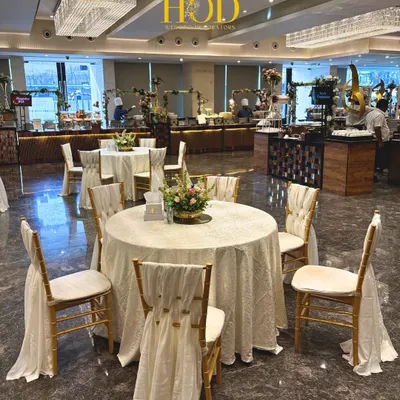 An elegant round table dining setup with beautifully draped chairs and a simple floral centerpiece, perfect for a sophisticated wedding reception.