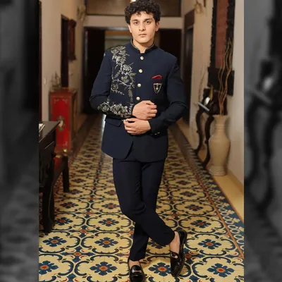 This navy blue Bandhgala suit is a perfect example of modern royalty. It features asymmetrical gold embroidery that flows from the shoulder down the chest, paired with a custom pocket crest. The entire look is tailored for a sharp, commanding presence.