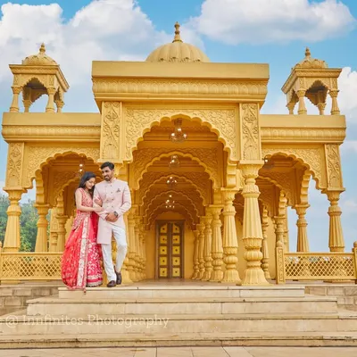 A full view of our stunning golden palace set, providing a majestic backdrop for this couple's pre-wedding portrait in coordinated traditional Indian outfits.
