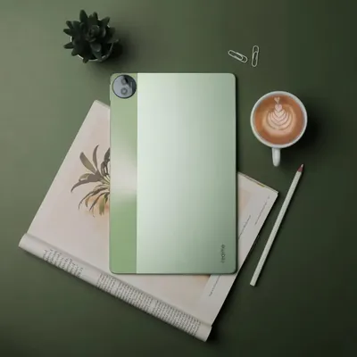 A top-down flatlay of the realme Pad 2, styled with a coffee cup, a notebook, and a plant to create a productive and creative workspace vibe.