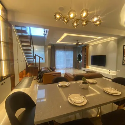An open-plan living and dining area creates a sense of spaciousness. I used a statement chandelier and recessed ceiling lights to define the dining space while keeping it connected to the living room.