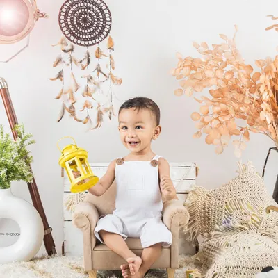 A happy little boy in a simple, bright white outfit, sitting in a mini armchair. This lifestyle setup with a dreamcatcher is one of my favorites.