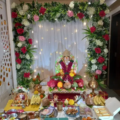 This is a full view of a home Ganpati setup, showing how our floral arch frames the idol and the entire puja area. The mix of red, pink, and white roses with green foliage creates a vibrant and celebratory atmosphere.