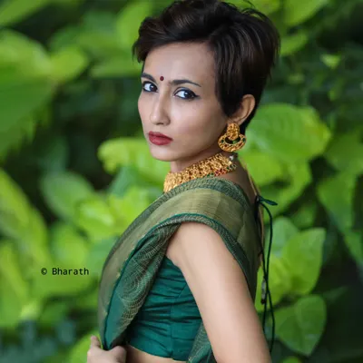 A bold and modern take on ethnic wear. This portrait features a model with a pixie cut wearing a traditional green silk saree, creating a striking contrast that challenges conventions.