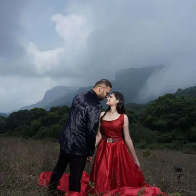 An intimate moment from a pre-wedding shoot against a stunning mountain backdrop. The makeup was designed to stand out yet look natural in the dramatic, cloudy lighting, pairing perfectly with her bold red gown.