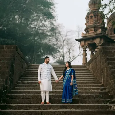 Hand in hand, Ankush and Aishwarya ascend the ancient stone steps at Sangam Mahuli. This wide shot captures the scale of the historic temple, making their journey together feel epic and significant.