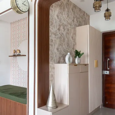The foyer of 'The Flux Abode' features a mix of textures and shapes, with fluted cabinets, curved wooden frames, and a vintage-style clock.