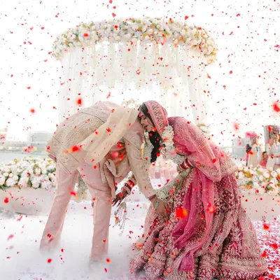 A moment of playful reverence during the varmala ceremony. The shower of petals and clouds of smoke create a magical, dreamlike atmosphere for this key ritual.
