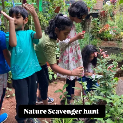 Young explorers on a mission during our Nature Explorer Camp. A scavenger hunt in a lush garden setting encourages them to look closely at plants and search for tiny creatures, honing their observation skills.