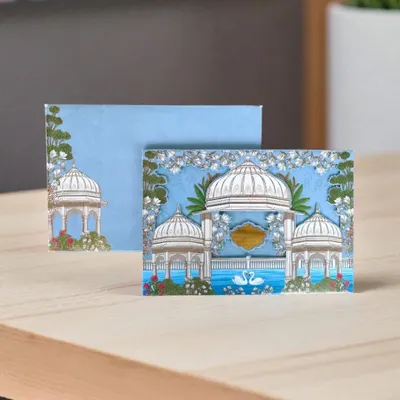 This Pichwai-themed card features serene white gazebos and swans against a sky-blue background, offering a peaceful and artistic announcement for your wedding.