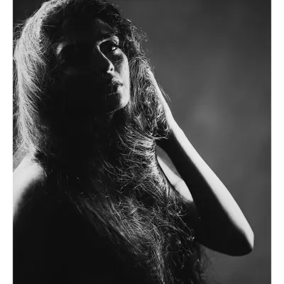 A dramatic black and white portrait where the hair becomes a key visual element. The strong side lighting carves out the subject's features and creates a powerful, artistic mood.