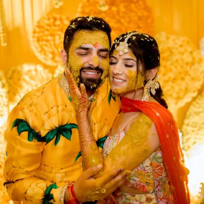 The quintessential Haldi shot. This photo captures the pure joy and playful mess of the ceremony, a moment of love and laughter that is truly priceless.