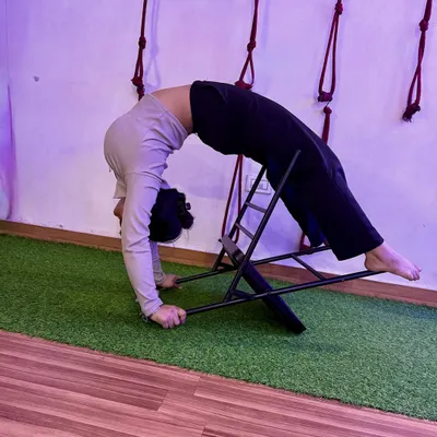 Using a chair to support a deep backbend. This prop helps open up the thoracic spine safely, allowing for a greater range of motion in Urdhva Dhanurasana.