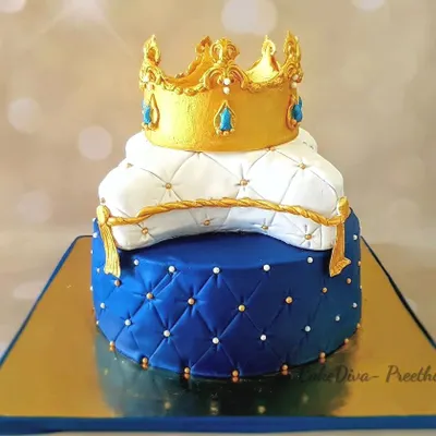 A royal birthday cake for a little prince's first birthday. This two-tier cake features a royal blue quilted fondant base and a white pillow tier, topped with a hand-sculpted golden fondant crown. The flavor inside was a rich chocolate hazelnut.