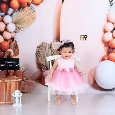 A beautiful portrait of a young girl in a pink dress, sitting in a boho-chic setup. The sign "Growing With Grace" perfectly captures this stage of her childhood.