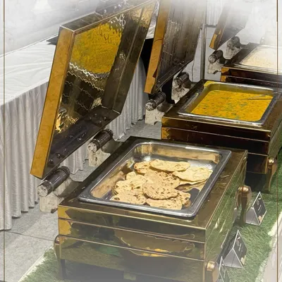 Our buffet setups are a feast for the eyes, featuring elegant brass and copper chafing dishes. Here, we showcase a spread of classic Indian main courses, including dal and fresh rotis.