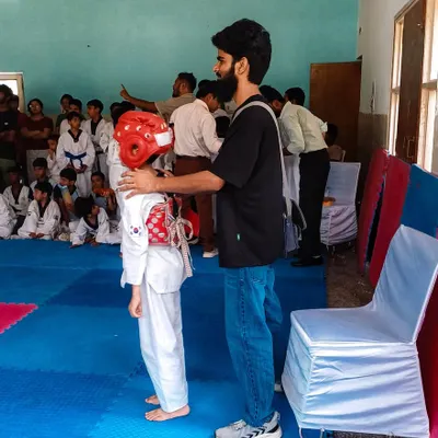 As a coach, I ensure my students are properly protected before they begin sparring, adjusting a student's headgear.