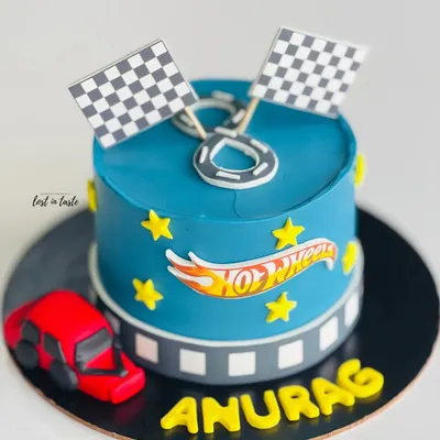 A Hot Wheels themed cake for a young racing fan. This design features a vibrant blue buttercream, the Hot Wheels logo, checkered flags, and a toy car.