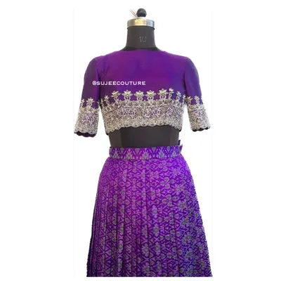 A full view of the custom purple Ikkat lehenga set on a mannequin. The outfit includes a pleated lehenga skirt and a raw silk blouse with intricate silver hand embroidery on the sleeves and hem.