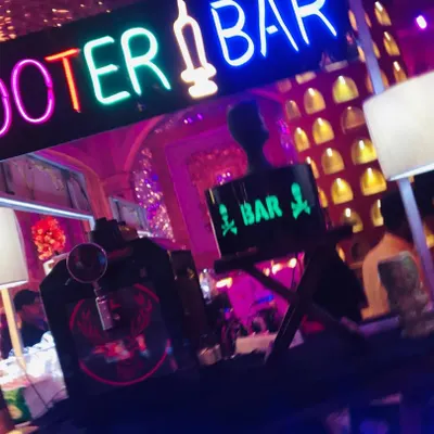 My 'Shooter Bar' is designed to be the life of the party. This setup features a bold, colorful neon sign, a Jägermeister tap machine, and unique decor for a fun vibe.