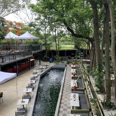 This is the view of our brewery's outdoor seating area. The tables are set alongside a serene water channel, surrounded by trees, offering a dining experience that feels miles away from the city.