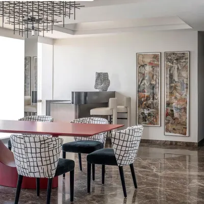 For this playful dining area, we paired a bold red metal dining table with chairs upholstered in a custom black-and-white print. The entire setting is designed to feel like a playground for art and color.