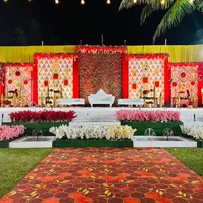 This grand reception stage is a celebration of traditional Indian design. I used panels with classic motifs, a backdrop of red roses, and elegant white seating to create a royal and opulent look.