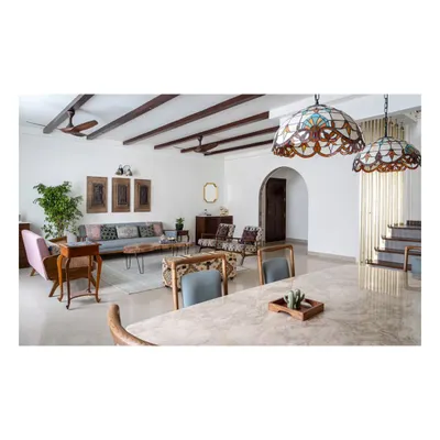 The open-plan living and dining area of our 'Spanish Country Home' project. Walnut-hued wooden rafters span the ceiling to conceal wiring and add vintage allure, while distinct furniture groupings and rugs delineate the spacious layout.