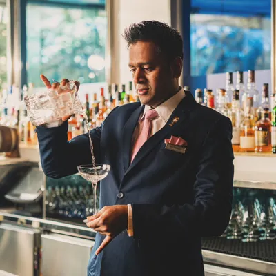 A bartender at Yauatcha expertly pouring a cocktail. This action portrait captures a moment of focus and skill, highlighting the craftsmanship that goes into every drink and adding a human touch to the bar experience.