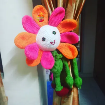 This large, colorful flower doll curtain holder is designed to bring a smile to your face. Its long arms wrap around the curtain, adding a bright and cheerful touch to the room's decor.