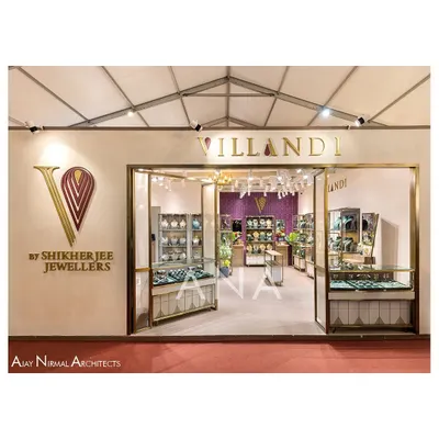 The main entrance to the Villandi Jewellers stall at Bridal Asia '23. The design features a clean, off-white facade with elegant brass-framed glass, creating a luxurious and inviting storefront that allows glimpses of the collection inside.